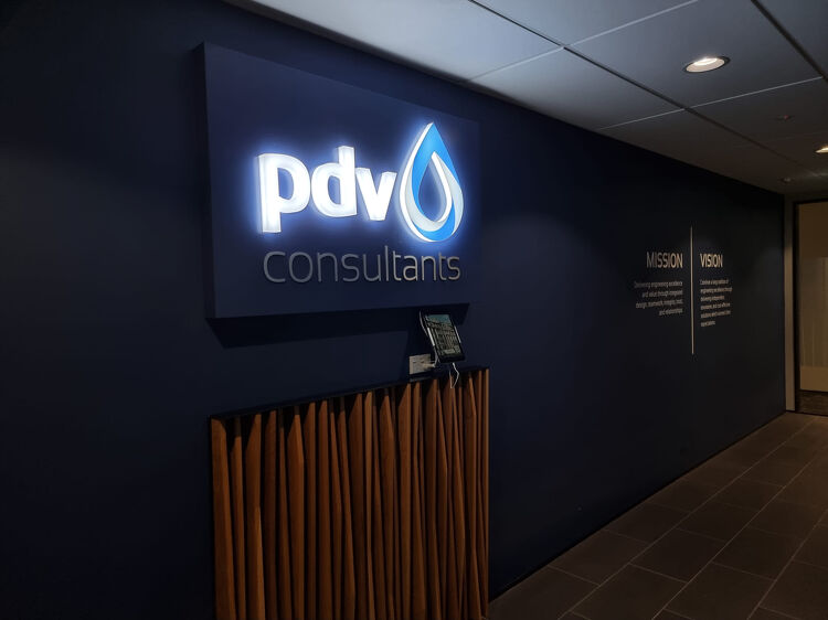 PDV Consultants illuminated sign in a reception area with mission and vision wall text
