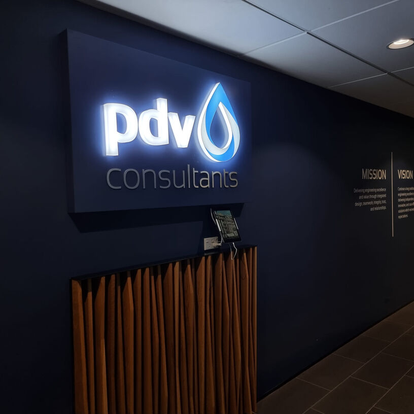 Why PDV Consultants? PDV Consultants illuminated sign in a reception area with mission and vision wall text